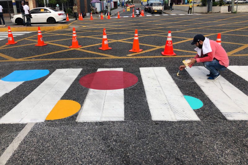 Hombre pintando círculos de colores en paso de peatones